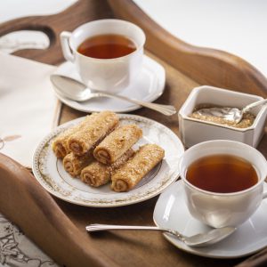 tray with a plate of fennome pastries, hot tea, and demerara sugar