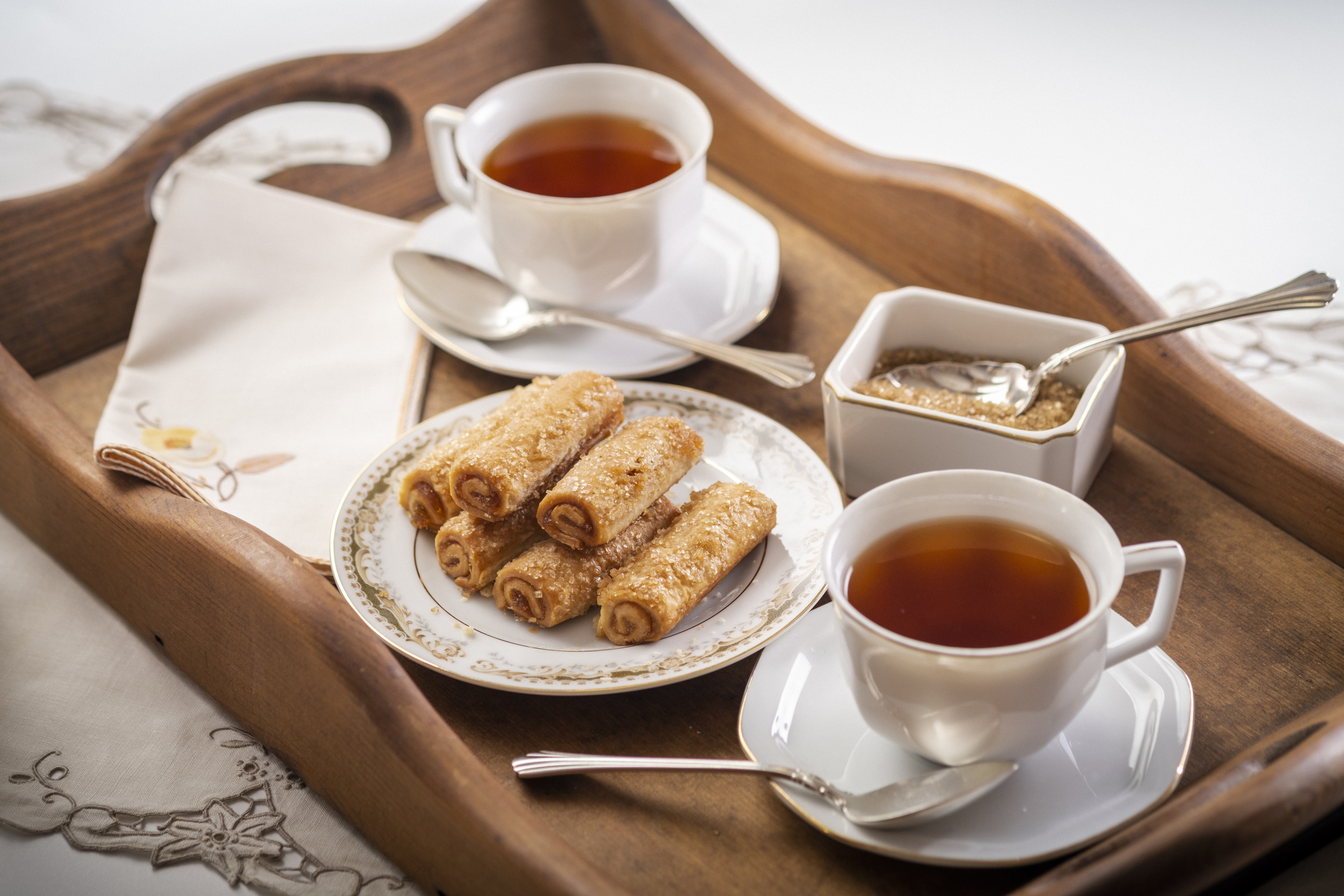 tray with a plate of fennome pastries, hot tea, and demerara sugar